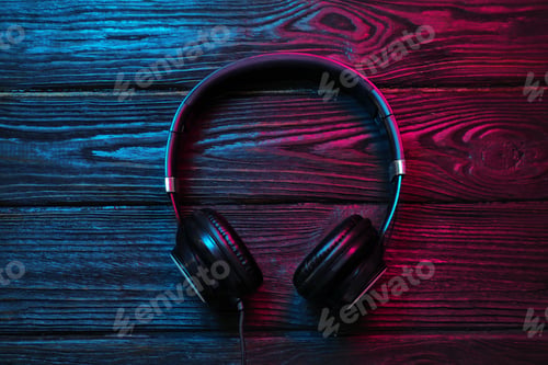 Preview: Stylish modern headphones with earmuffs on wooden background, top view