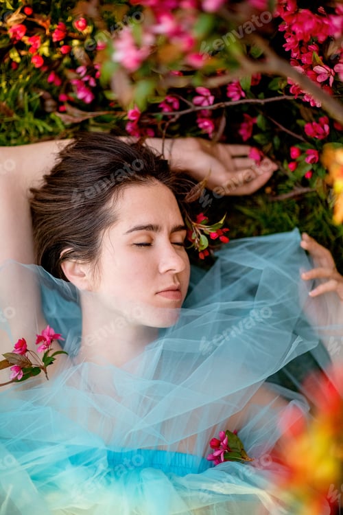 Preview: beautiful dark-haired girl lies on the grass near a flowering tree