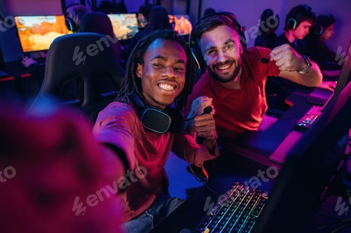 Preview: Black man is making selfie, smiling. Gamers are playing video game by computers
