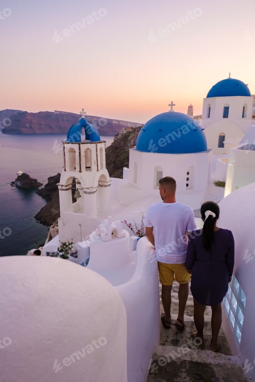 Preview: Men and women visit the whitewashed Greek village of Oia during vacation in Santorini with blue dome