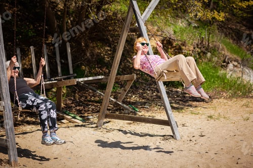 Preview: Two elderly women joyfully swinging on a swing