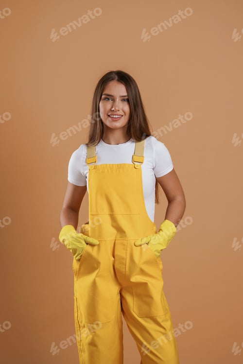 Preview: Hands in pockets, gardener is standing. Young pretty woman is against background in the studio