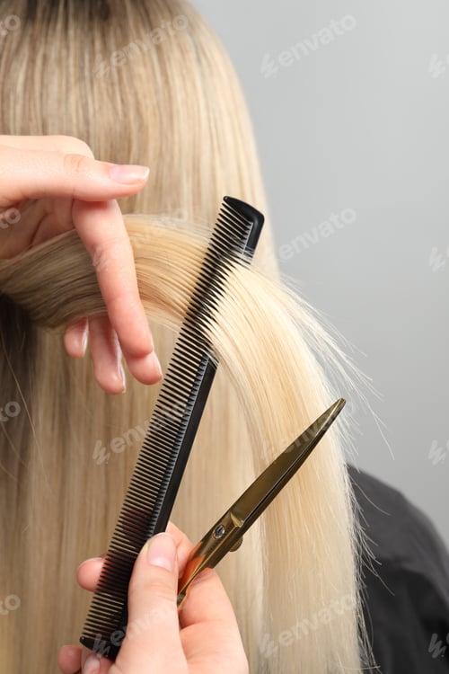 Preview: Hairdresser cutting client's hair with scissors on light grey background, closeup