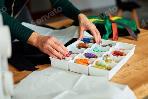 Preview: Step by step, woman's dressmaker hand pulls the thread out of the box