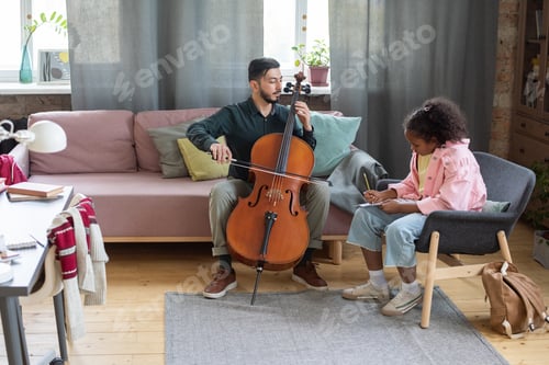 Preview: Young teacher of music showing his pupil how to play cello