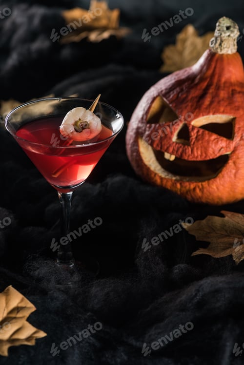 Preview: red cocktail near Halloween pumpkin and maple dry yellow leaves on black background
