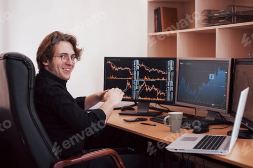 Preview: Stock broker looking at graphs, indexes and numbers on multiple computer screens