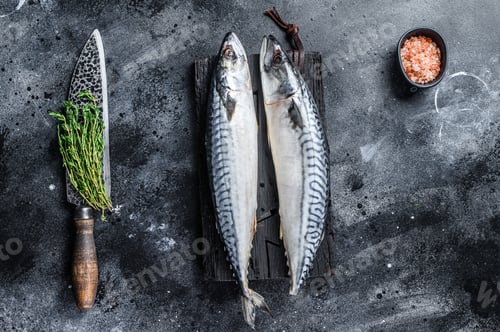 Preview: Raw fish Mackerel on a wooden cutting board. Black background. Top view