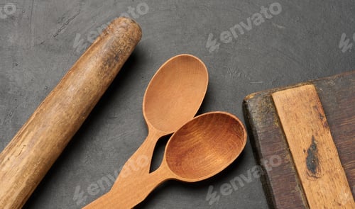 Preview: Wooden spoons, cutting board and rolling pin on a dark surface
