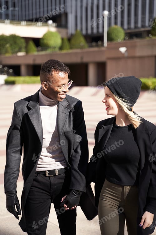 Preview: Cheerful diverse couple walking on street