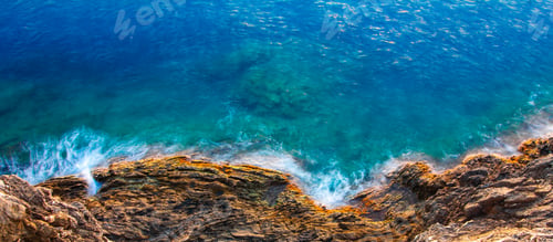 Preview: Aerial view of sea waves and rocky coast with turquoise and sapphire clear water. Long exposure