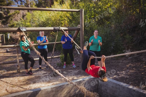 Preview: Fit woman climbing a rope during obstacle course training