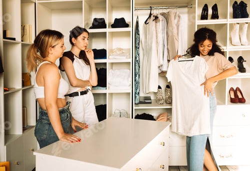 Preview: Charming teenage girls of different races choose clothes in the store.