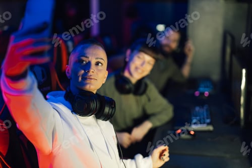 Vista previa: Una chica gamer con auriculares se toma selfies en un cibercafé.