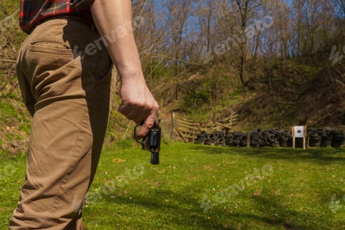 Preview: Unrecognizable man with revolver preparing to shot target on shooting range outdoors.