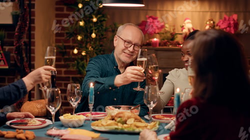 Preview: Cheerful multicultural family members toasting champagne while enjoying Christmas dinner