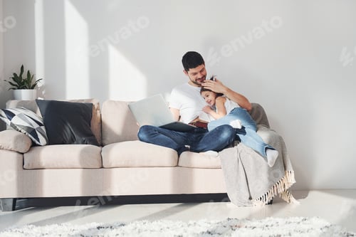 Preview: Happy father with his daughter spending free time with laptop at home together