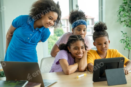 Preview: Young African American children sitting at school desk attentively listening to his teacher.