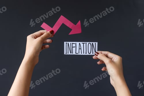 Preview: Hand holding Inflation text and graph chart arrow pointing down
