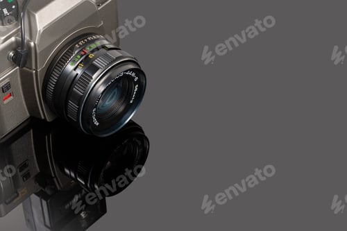 Preview: Closeup shot of a photo camera on a reflective surface