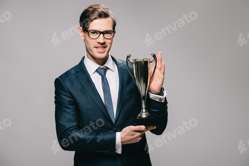 Preview: handsome businessman holding trophy in hands isolated on grey