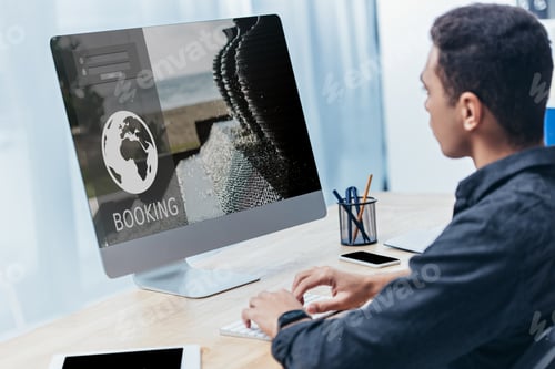 Preview: young businessman using desktop computer with booking website screen in office