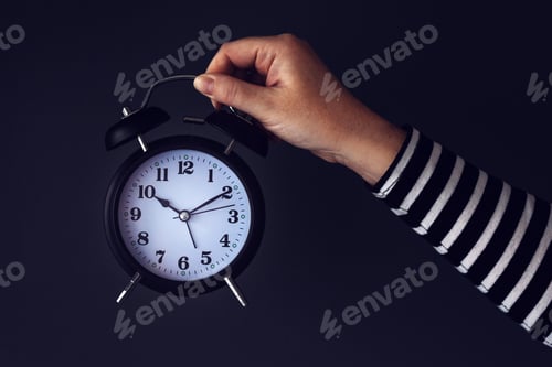 Preview: Time is passing, female hand with vintage alarm clock