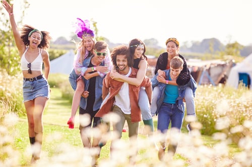 Preview: Group Of Friends Walking Back To Tent After Outdoor Music Festival With Men Giving Women Piggybacks