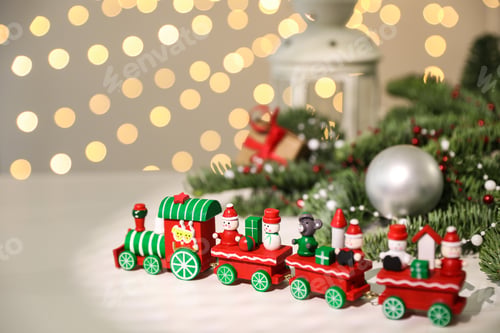 Preview: Toy train and Christmas decor on white table against blurred lights