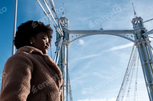 Preview: Young black woman standing under historical London bridge.