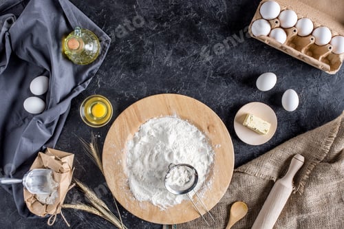 Preview: flat lay with various ingredients for bread baking and cutlery on dark marble surface