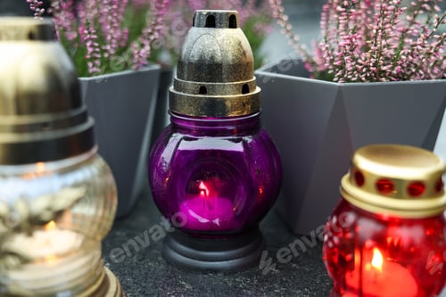 Preview: Grave lights with potted heather on granite surface at cemetery, closeup