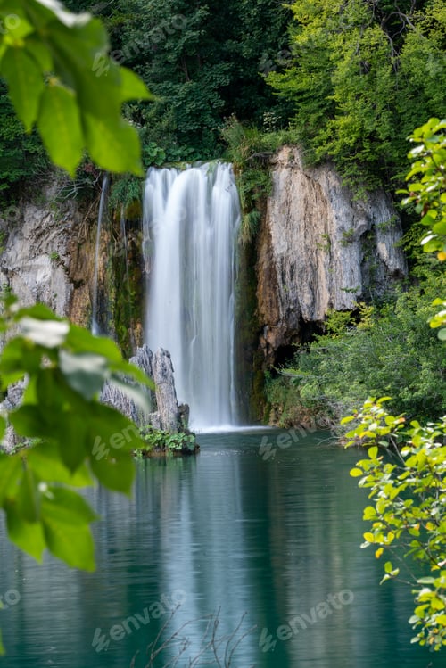 Preview: Vertical shot of the beautiful waterfall surrounded by green vegetation.