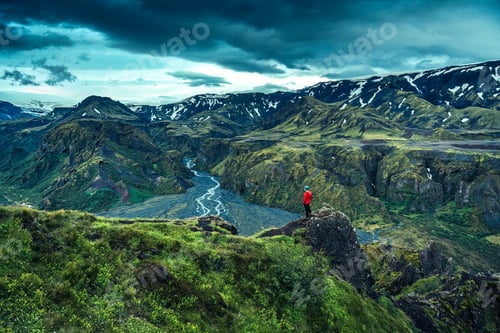 Preview: Male tourist standing on Valahnukur peak with volcanic mountain and glacier river at Thorsmork