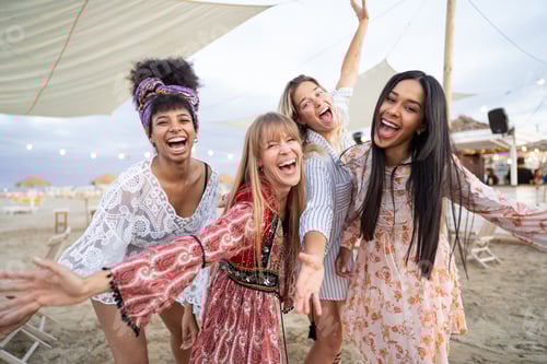 Preview: Smiling multiracial girls dancing at sunset beach party - four young girls having fun at bar