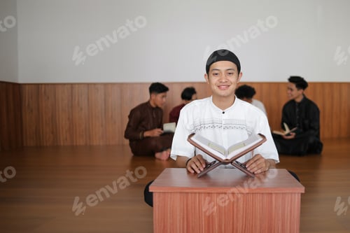Preview: Portrait Of Young Muslim Boy Smiling And Sitting With Qur'an At The Mosque