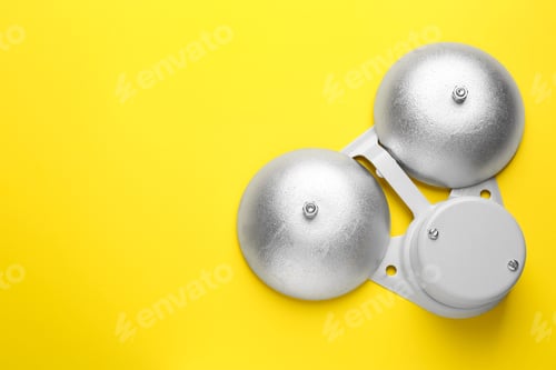 Preview: Modern electrical school bell on yellow background, top view. Space for text