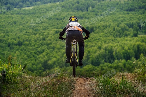 Preview: athlete rider downhill trail in background forest