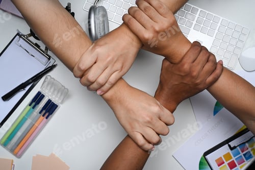 Preview: multiracial group hands holding each other wrist on office table.