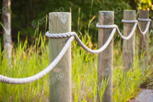 Preview: Closeup of fence made of rope and wooden pole in park