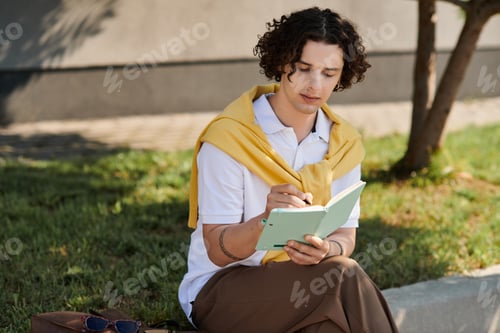 Preview: Handsome young man in stylish business attire enjoys a peaceful moment writing outdoors