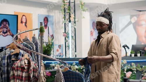 Preview: Man closely looking at shirts in mall