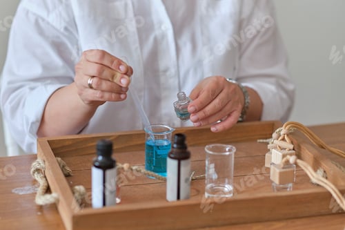 Preview: Close-up of a pipette with oil and a glass bottle. woman pouring perfume in bottle.
