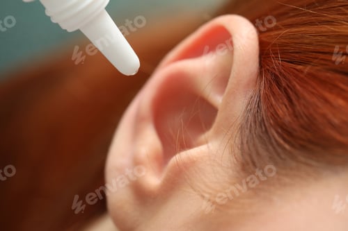 Preview: Woman applying medical ear drops, macro view