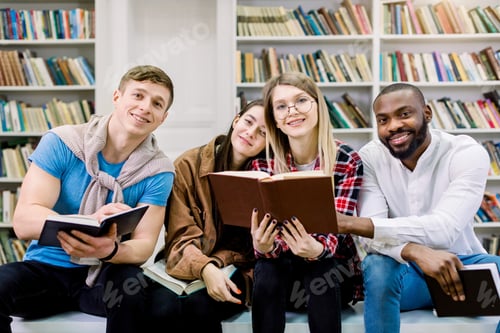 Preview: Four multiethnic cheerful students friends in the library, reading books, communicating and spend