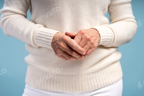 Preview: Closeup, retired woman wearing casual clothes, selective focus on hands, isolated on blue background