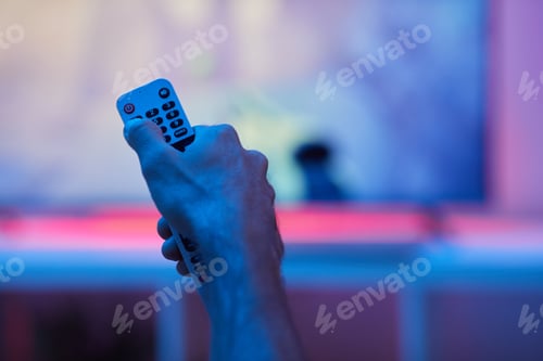 Hand Holding Remote Control in Blue Light