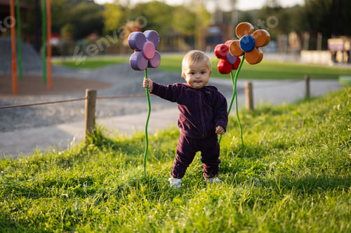 Preview: Adorable toddler playing with colorful flowers in a sunny park