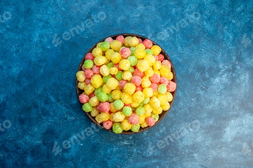 Preview: Above view of delicious coloured sweets in a small brown pot on blue background