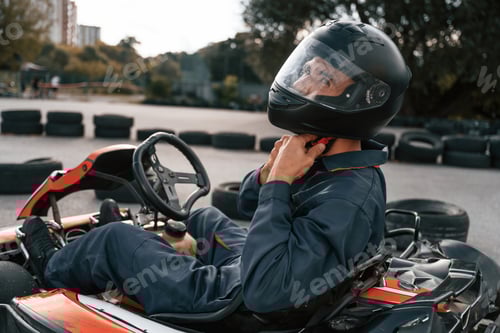 Preview: Side view, wearing the safety helmet. Man is outdoors, kart racing conception